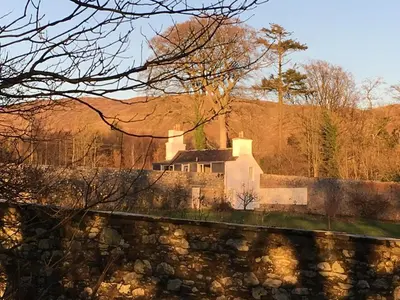 a house sitting on top of a stone wall at Garden Cottage in Carsluith