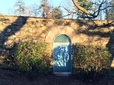 a stone wall with a blue door with a window at Garden Cottage in Carsluith