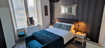 a bedroom with a bed and a blue chair at Troon Beachcombers in Troon