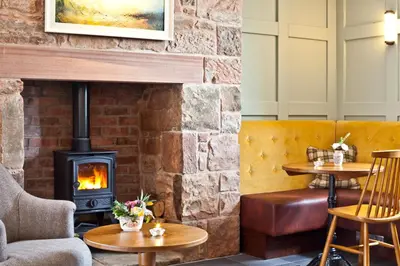a fireplace in a restaurant with two tables and chairs at Pentonbridge Inn - Restaurant with Rooms in Carlisle