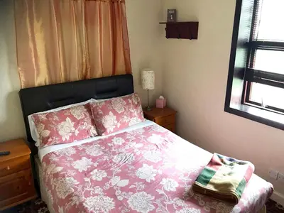 a bedroom with a bed with pink sheets and a window at Ferintosh Guest House in Dumfries