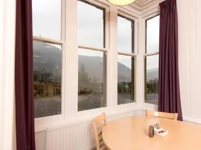 a table and chairs in a room with windows at YHA Buttermere in Buttermere
