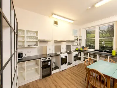 a kitchen with white cabinets and a table and chairs at YHA Buttermere in Buttermere