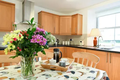 a vase of flowers on a table in a kitchen at Longhill Farmhouse in Whithorn