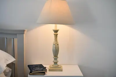 a lamp sitting on a table next to a bed at Longhill Farmhouse in Whithorn