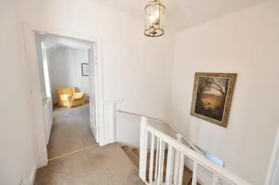 a hallway with a staircase with a painting on the wall at Longhill Farmhouse in Whithorn