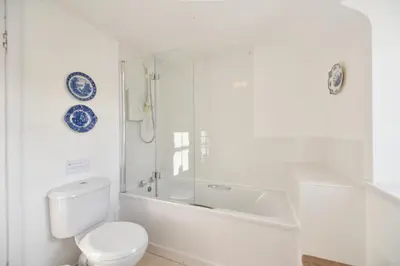 a white bathroom with a toilet and a bath tub at Longhill Farmhouse in Whithorn