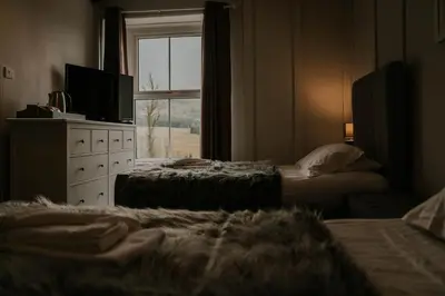 a bedroom with two beds and a television and a window at Troutbeck Inn in Troutbeck