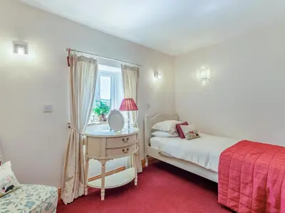 a bedroom with a bed and a desk with a mirror at New Park Farm - Church Cottage in Ireby
