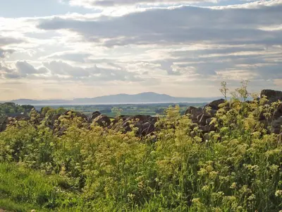 a field of grass and rocks with mountains in the background at New Park Farm - Church Cottage in Ireby