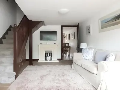 a living room with a white couch and a fireplace at Woodpecker Cottage in Westward