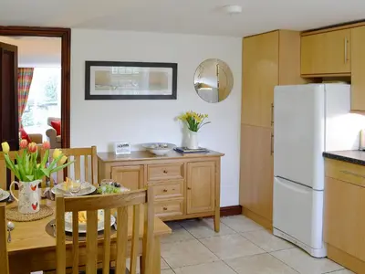a kitchen with a table and a white refrigerator at Woodpecker Cottage in Westward