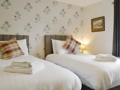 two beds sitting next to each other in a bedroom at Philip's Cottage in Keswick