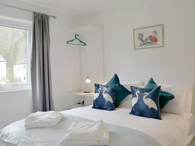 a bedroom with a bed with blue pillows and a window at Philip's Cottage in Keswick