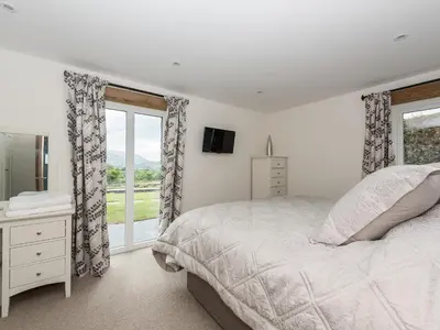 a white bedroom with a bed and a window at The Hoggest in Threlkeld