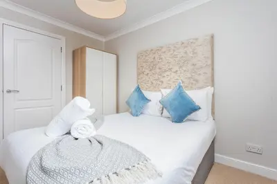 a bedroom with a white bed with blue pillows at Carrick Retreat - Donnini Apartments in Ayr