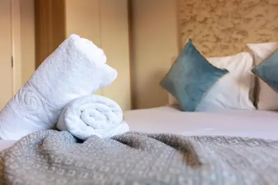 a pile of towels sitting on top of a bed at Carrick Retreat - Donnini Apartments in Ayr