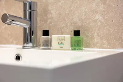 a sink with three bottles of soap and a faucet at Carrick Retreat - Donnini Apartments in Ayr