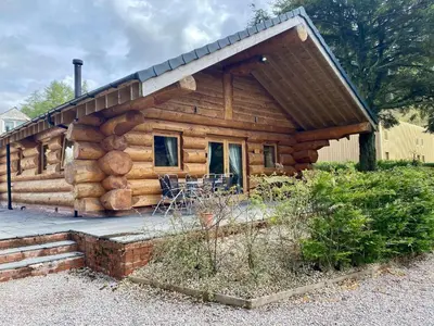 a log cabin with a porch and chairs in front at Ewes Water Log Cabins in Langholm