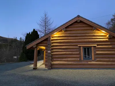 a log cabin with lights on the side of it at Ewes Water Log Cabins in Langholm