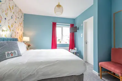 a bedroom with a large bed and a red chair at Rickerby Grange in Keswick