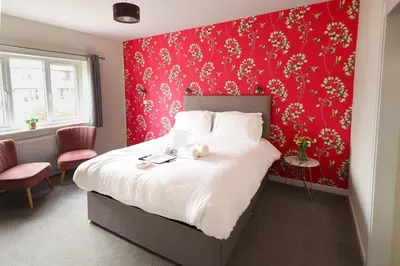 a bedroom with a large bed with a red wall at Rickerby Grange in Keswick