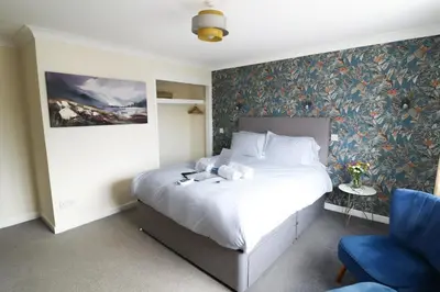a bedroom with a large bed and a blue chair at Rickerby Grange in Keswick