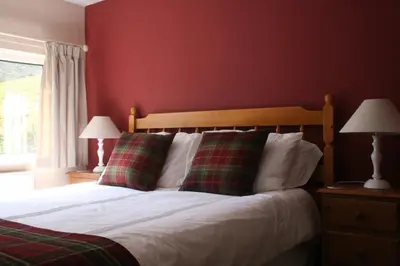 a bedroom with a bed with red walls and two lamps at StoneyFell in Keswick