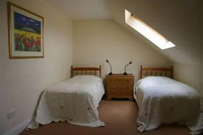 a bedroom with two beds and a skylight at Dairy Cottage in Ayr
