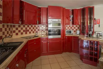 a red kitchen with red cabinets and appliances at Dairy Cottage in Ayr