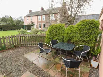 a patio with a table and chairs and a fence at Woodpecker in Ivegill