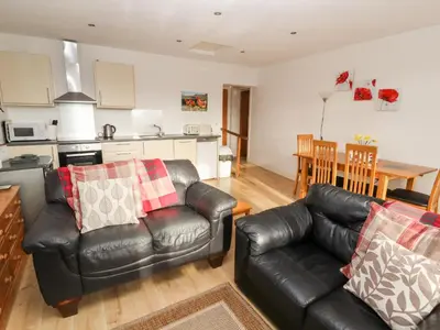 a living room with two leather couches and a kitchen at Woodpecker in Ivegill