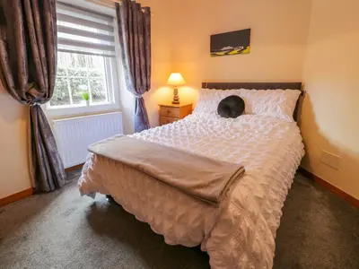 a cat laying on a bed in a bedroom at Rose Cottage in Stranraer