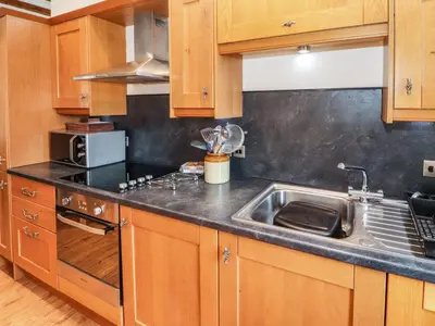 a kitchen with wooden cabinets and a sink at The Hayloft in Keswick