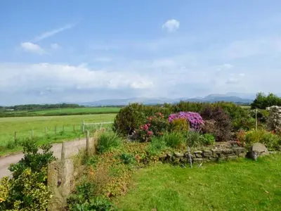 a garden with flowers and a fence in a field at Surprise View in Holmrook