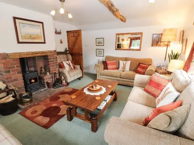 a living room with a table and a fireplace at Fell Cottage in Wigton