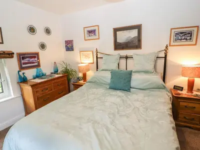 a bedroom with a large bed with blue pillows at Fell Cottage in Wigton