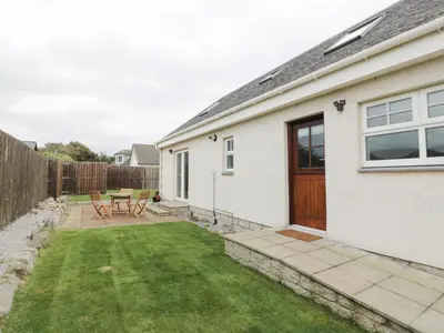 a backyard with a table and chairs and a house at The Bothy in Mainsriddle