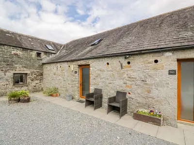 a stone building with two chairs in front of it at The Byre in Newton Stewart