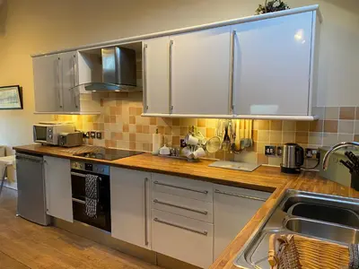 a kitchen with stainless steel appliances and wooden counter tops at Stable Cottage in Wigton