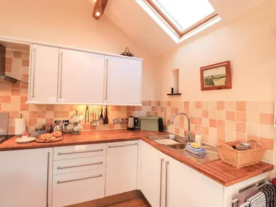 a kitchen with white cabinets and a skylight at Stable Cottage in Wigton