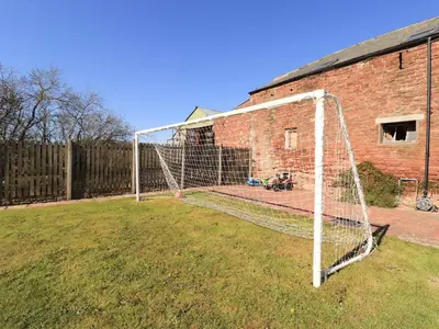 a soccer net in a yard next to a brick building at Stable Cottage in Wigton