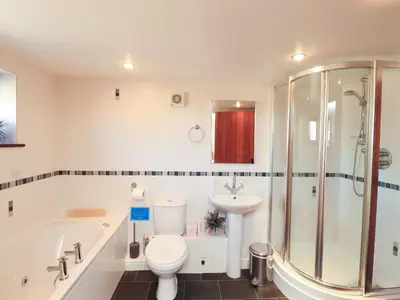 a bathroom with a tub and a toilet and a sink at Stable Cottage in Wigton