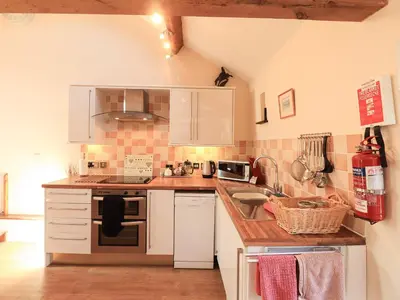 a kitchen with white cabinets and a stove top oven at Horseshoe Cottage in Wigton