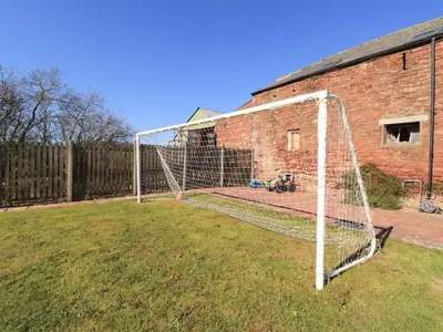 a soccer net in a yard next to a brick building at Horseshoe Cottage in Wigton
