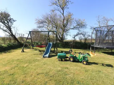 a playground with a toy tractor and a swing at Horseshoe Cottage in Wigton