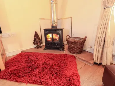 a red rug in front of a stove in a room at Horseshoe Cottage in Wigton