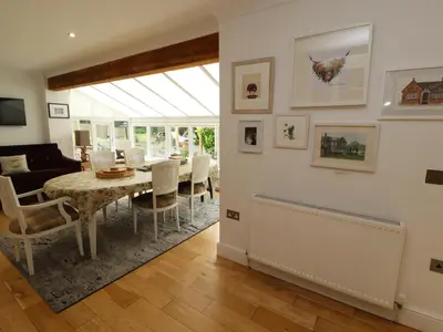 a dining room with a table and a living room at North Lodge in Annan