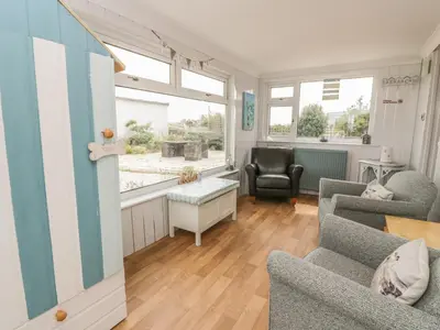 a living room with two chairs and a table at Wagtail Cottage in Mainsriddle