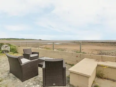 a patio with a table and chairs and the beach at Wagtail Cottage in Mainsriddle